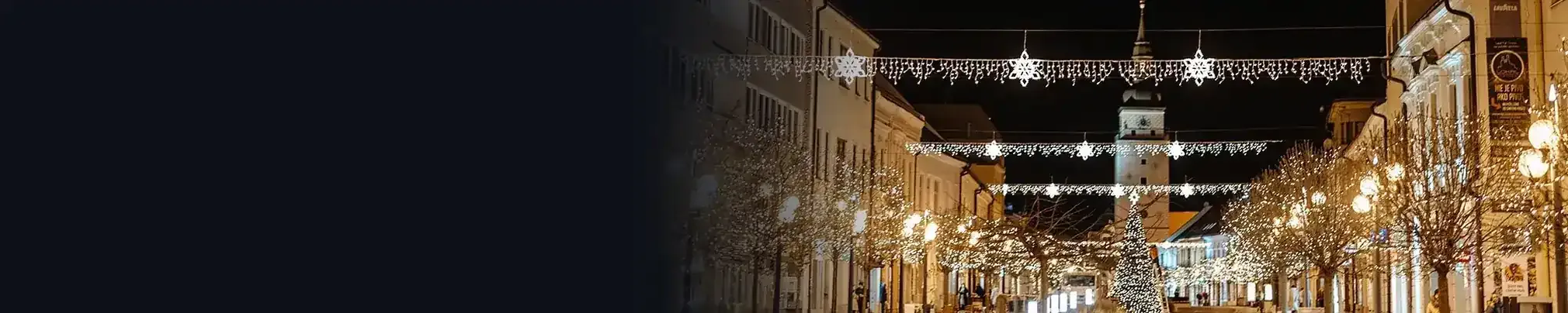 Éjszakai utca karácsonyi fénydíszekkel az utca felett és az oszlopokon